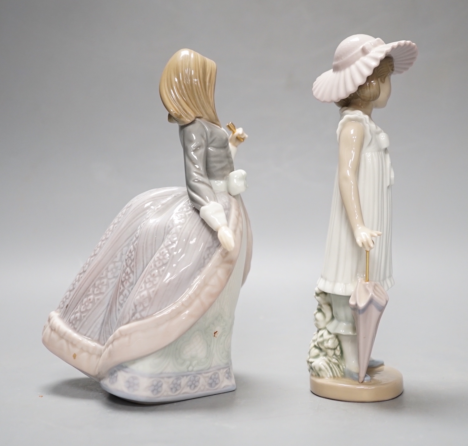 A Lladro figure of a lady with parasol, 18.5cm and a similar Nao figure